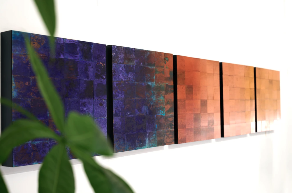 A polyptych of artworks by Sanne Terweij that use oxidised copper squares to fade from dark blue through to brown. 