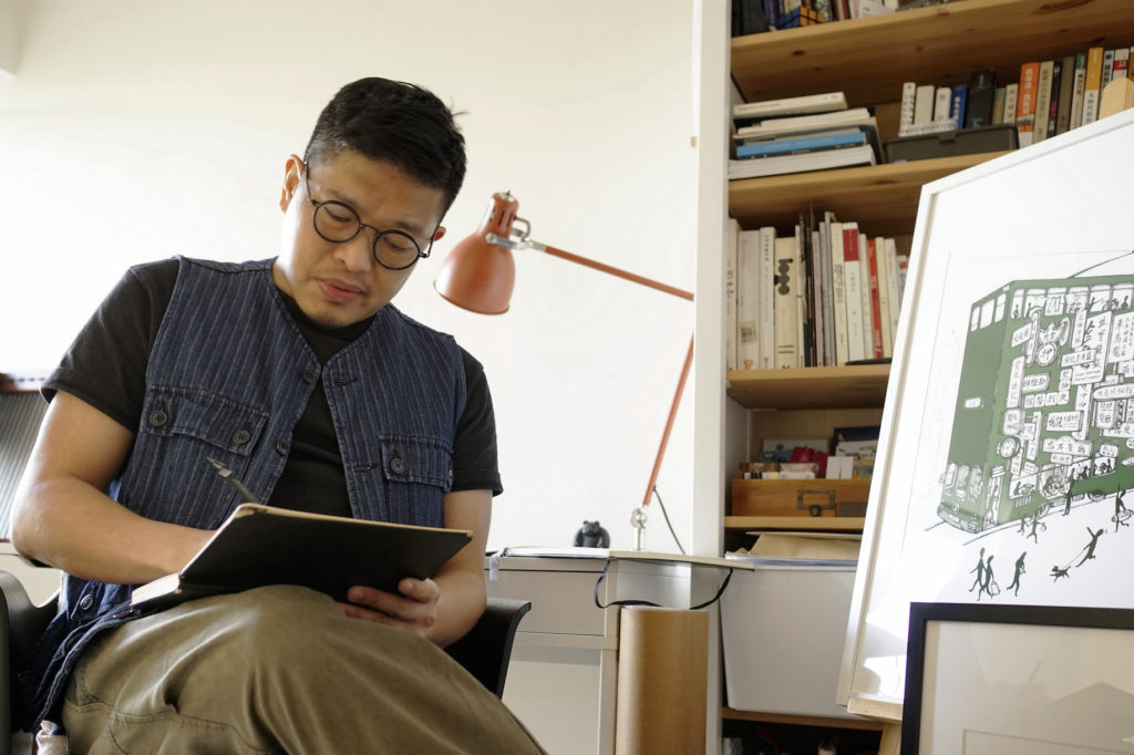 Rick Lo sitting in his studio, focusing and working on his sketchbook 