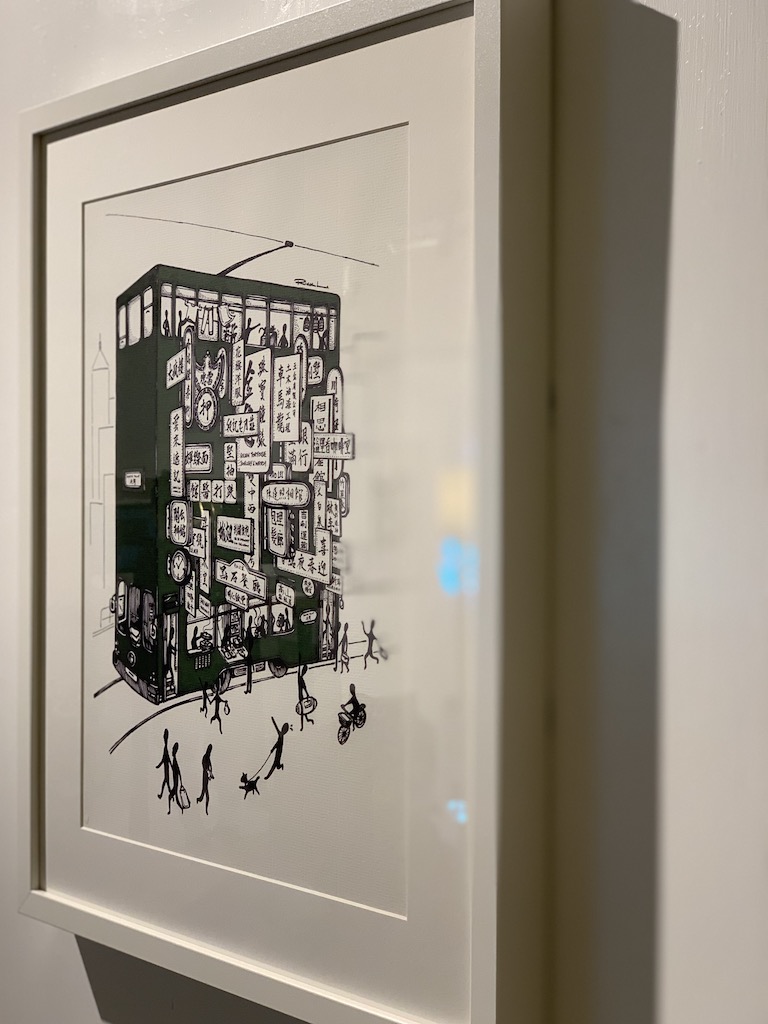 Rick Lo's "The Ancient Trail Of Hong Kong Tramways" mounted in frame exhibiting on wall 