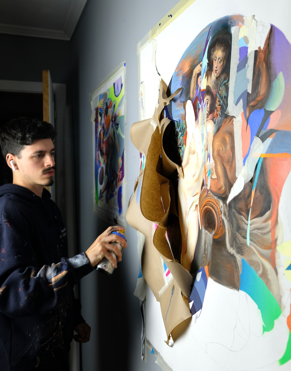 Murfin holding a spray can, working on a three-dimensions artwork hanging on wall