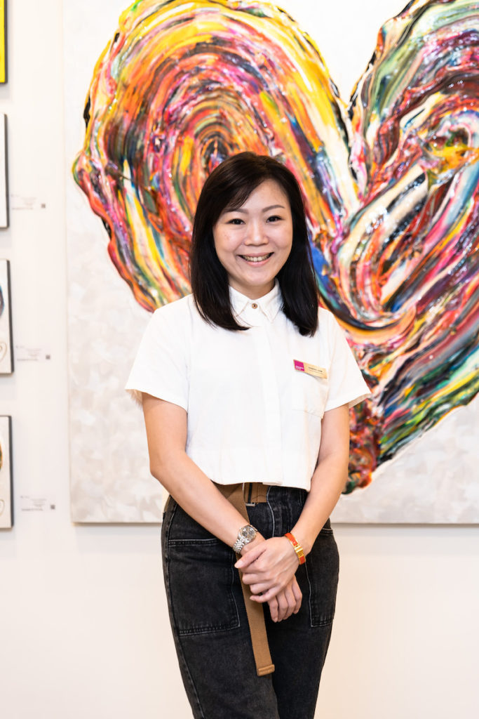 Bernice Lew, Financial Controller Asia, at the Singapore fair, stood in front of an abstract artwork that features a rainbow heart. 