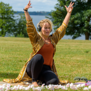 Teacher in a yoga pose sitting on a mat in nature