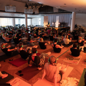 People sitting on yoga mats with headphones during a silent yoga session