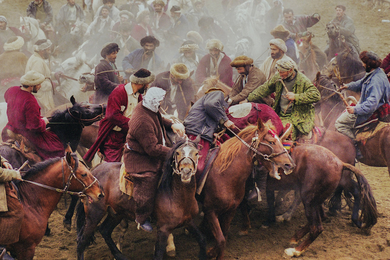 A photograph of local people playing the sport of Buzkashi, in which horse-mounted players attempt to place a goat or calf carcass in a goal. 