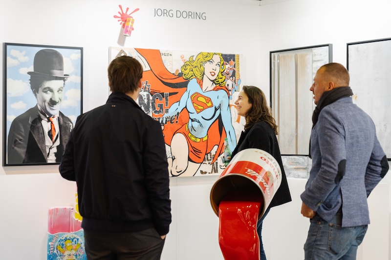 Three visitors admire a selection of urban art at Affordable Art Fair Amsterdam. 