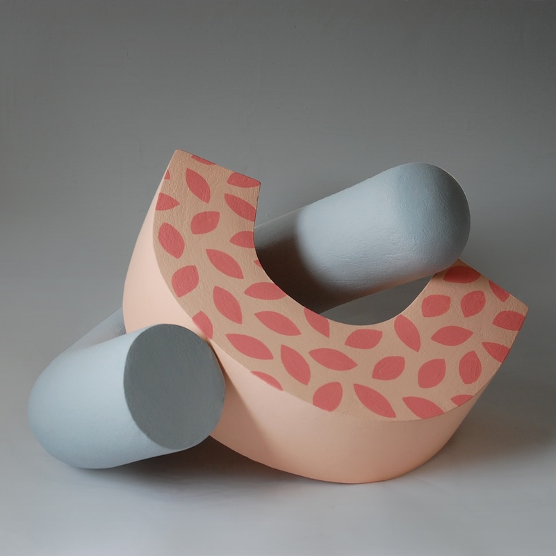A sculpture by Patricia Volk. A peach-coloured, c-shaped ceramic curled against a similar, grey c-shaped ceramic. 