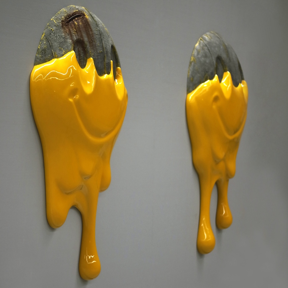 Two concrete cartoon smiley faces dripping in yellow paint. 