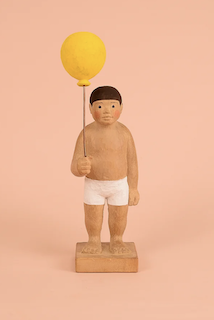 A half-naked boy holding a balloon.
